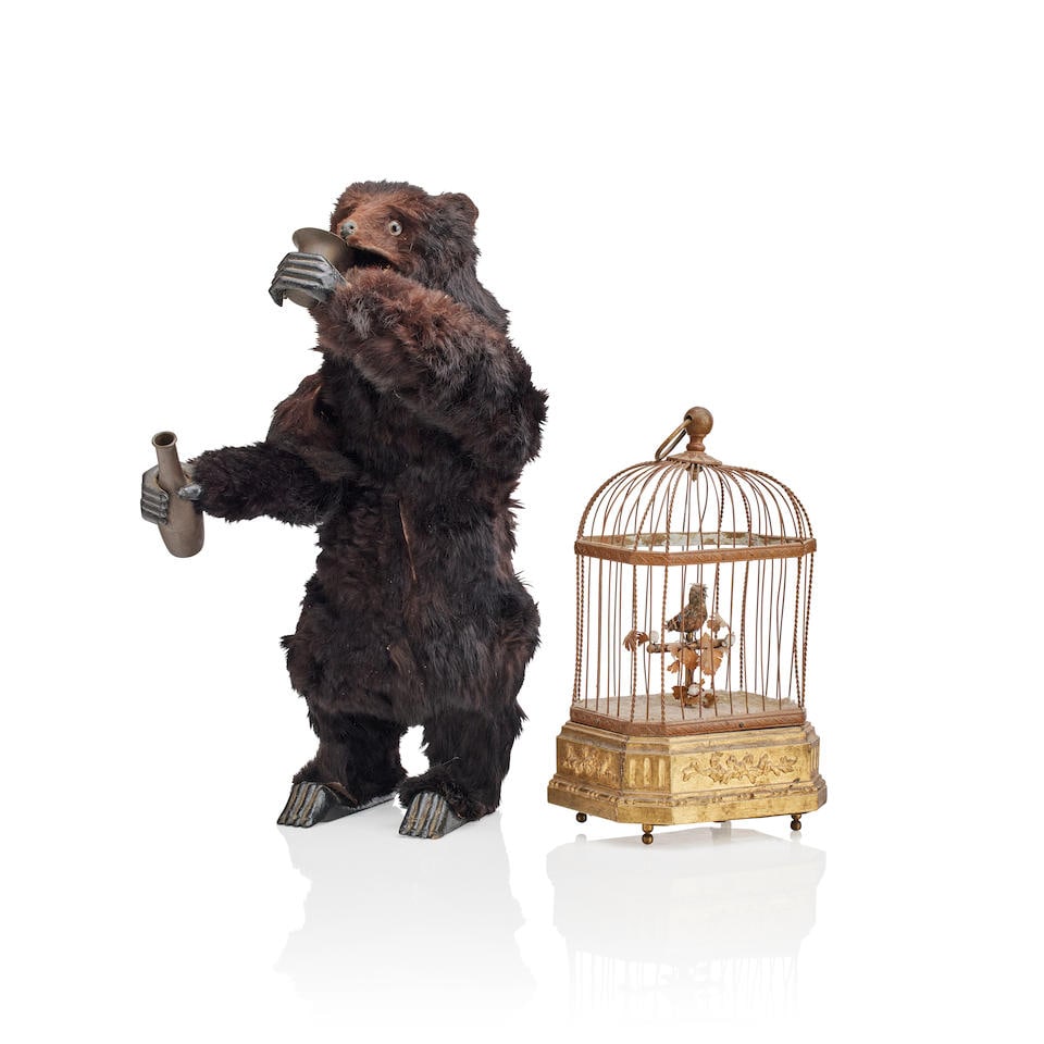 A 20th century caged singing bird automaton probably French, in the 19th century style: A 20th century caged singing bird automaton probably French, in the 19th century style The feathered bird with beak head and tail movements mounted on a floral entwined perch, the canted domed cage wi