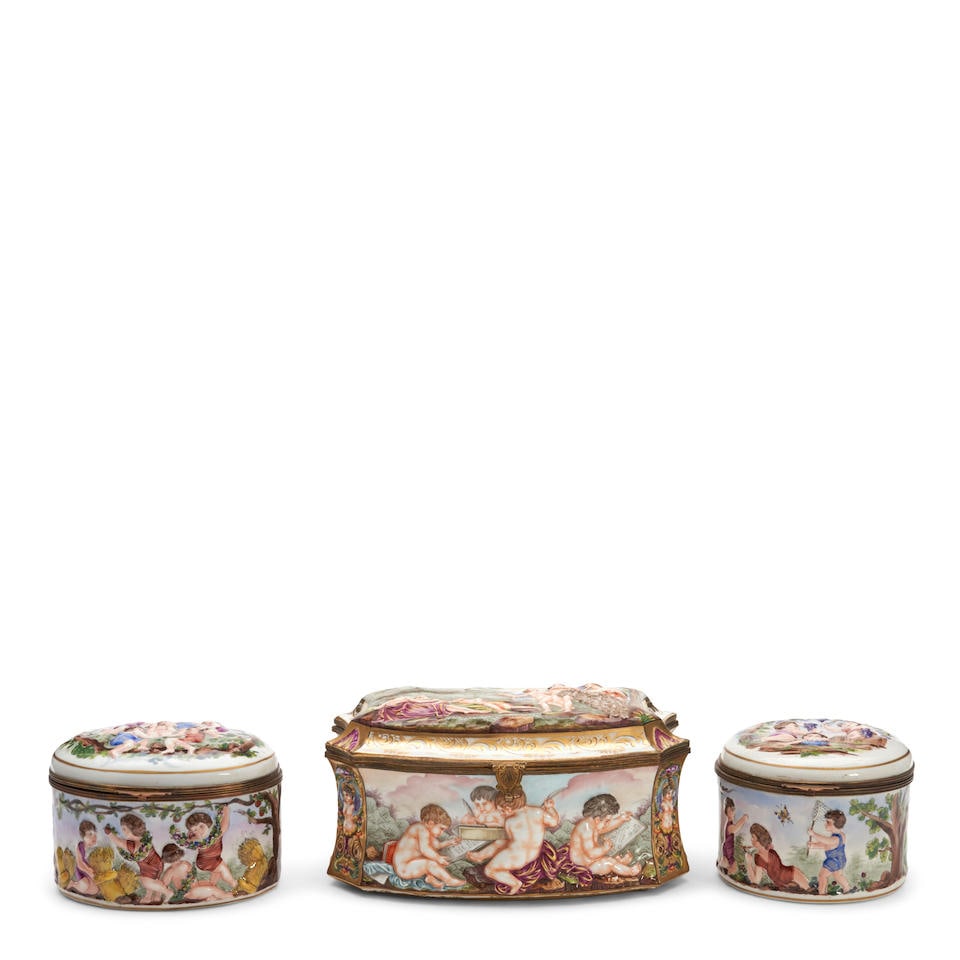 THREE CAPODIMONTE PORCELAIN BOXES Italy, late 19th century: THREE CAPODIMONTE PORCELAIN BOXES Italy, late 19th century with hinged lids, gold and polychrome enamel decorated and in high relief with classical figures and scenes, ht. to 5 5/8, wd. to 10 3/4 in.