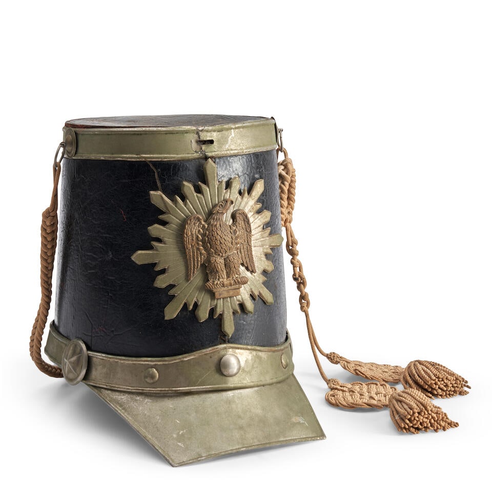 A RICHMOND LIGHT INFANTRY SHAKO.: A RICHMOND LIGHT INFANTRY SHAKO. Black leather body with a starburst emblazoned with an eagle on the front above a metal band and visor, the sides with braided cord and tassels; the interior with leat