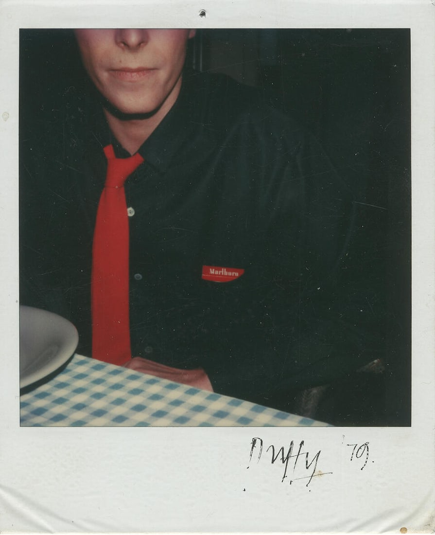 Brian Duffy (1933-2010): Autographed Polaroid of David Bowie with Marlboro Packet, 1979,: Brian Duffy (1933-2010): Autographed Polaroid of David Bowie with Marlboro Packet, 1979, Polaroid, featuring Bowie in a black shirt and red tie with a packet of Marlboro cigarettes in his shirt pocket
