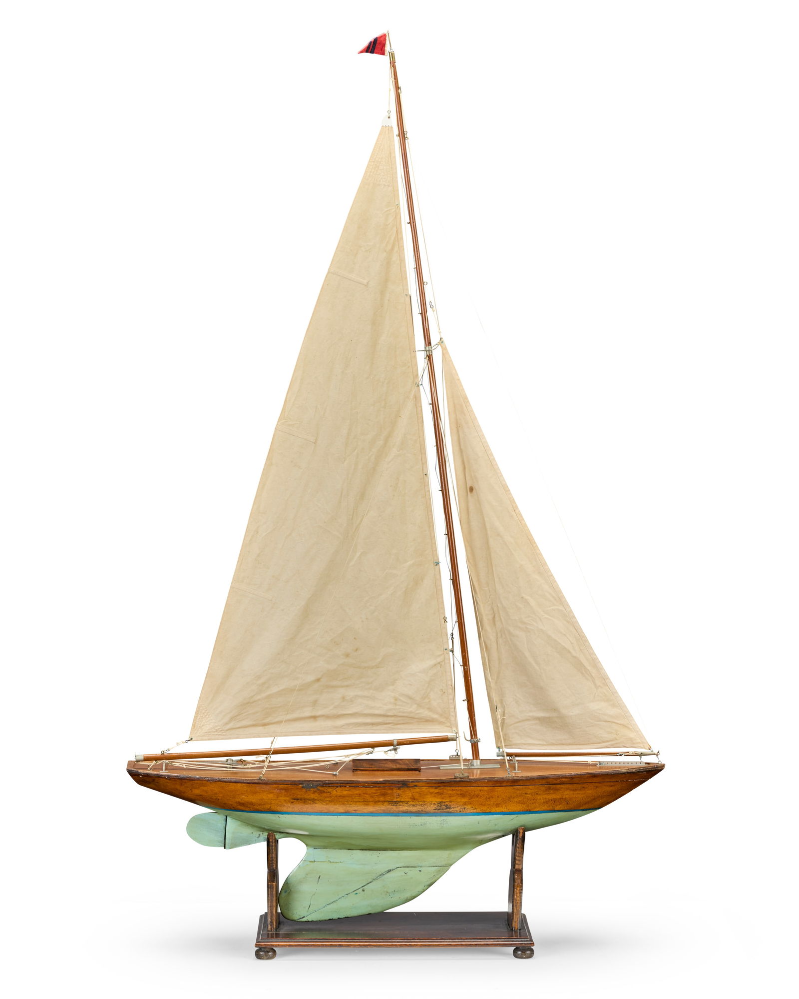 A pond yacht, early 20th century,: A pond yacht, early 20th century, with linen mail sail and jib, auto steering, wooden hull with lead weighted keel, on stand 158 x 91 x 25.5cm (62 x 36 x 10in) This lot is subject to the following lo