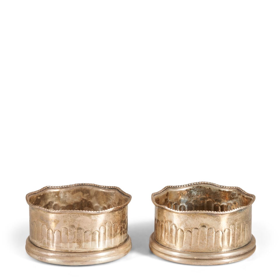 PAIR OF SILVER-PLATED WINE COASTERS Early 20th century,: PAIR OF SILVER-PLATED WINE COASTERS Early 20th century, Each with a scalloped and beaded rim, fitted with a turned wooden base, ht. 2 3/8, dia. 4 1/2 in. Footnotes: OVERALL CONDITION: Wear consistent