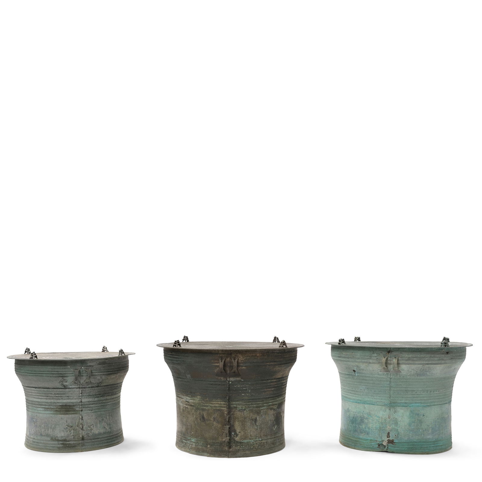 THREE BRONZE MOKO STYLE DRUMS20th century: THREE BRONZE MOKO STYLE DRUMS 20th century height of largest 19 1/2in (49.5cm); diameter 17 1/4in (43.8cm) Footnotes: Condition reports are not provided in catalog descriptions. The absence of a condi