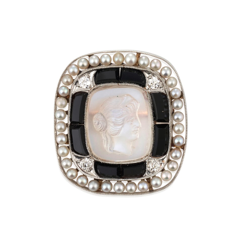 AN ART DECO MOONSTONE CAMEO, ONYX, SEED PEARL, AND DIAMOND BROOCH: AN ART DECO MOONSTONE CAMEO, ONYX, SEED PEARL, AND DIAMOND BROOCH The moonstone cameo depicting a maiden with upswept hair and diadem, framed by calibré-cut onyx and seed pearls, with old Europea