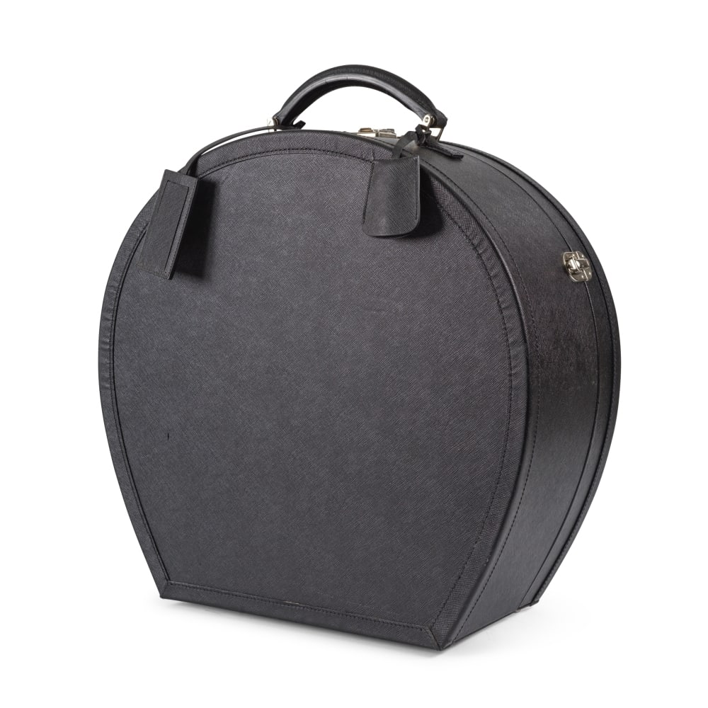 A Prada Hat Case: Prada. Boîte à chapeaux de forme circulaire en cuir noir façon cuir de Russie, poignée. Prada. Circular hat box in black leather with Russian leather effect, handle. Condition grad