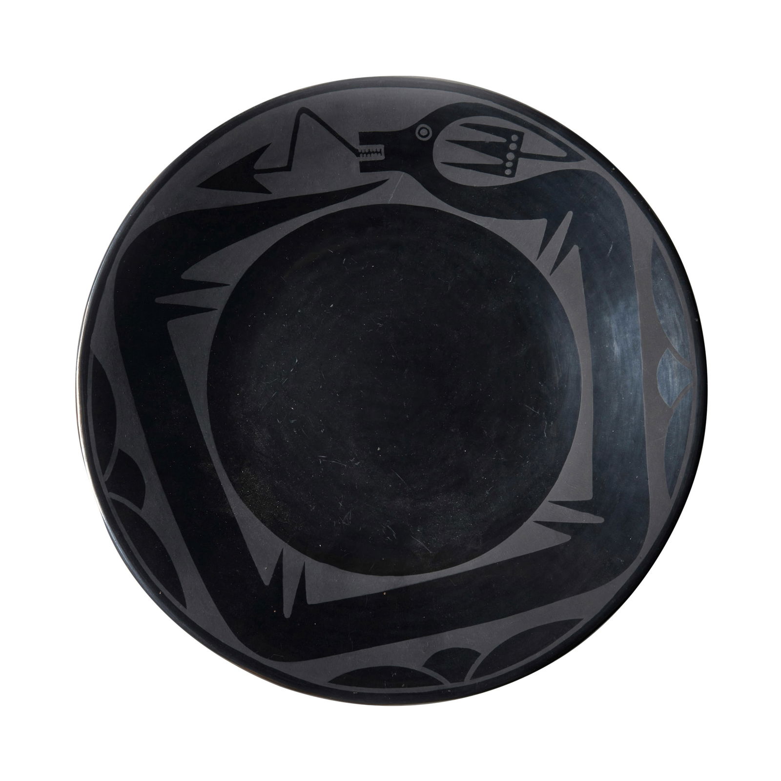 A Maria Martinez and Popovi Da blackware pottery plate: Maria Martinez and Popovi Da San Ildefonso Pueblo, (1887-1980) and (1923-1971), a blackware pottery plate, the outer border enclosing an encircling Avanyu, signed on the underside: Maria / Popovi. hei