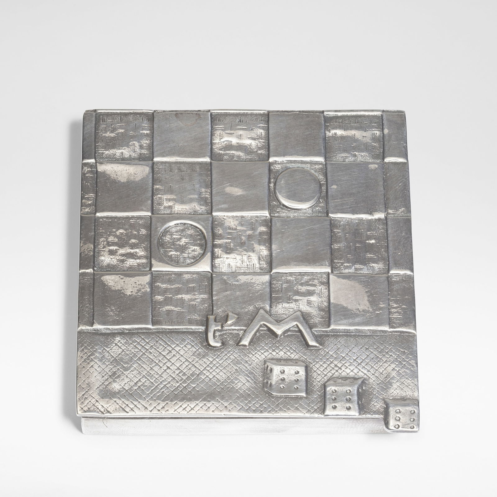 Line Vautrin 'Je t'aime beaucoup' poudrier, circa 1946: Line Vautrin 'Je t'aime beaucoup' poudrier, circa 1946 Silvered-bronze, mirror and fabric, the lid modelled in shallow relief with a game board, three dice and 't'M'. 6.8 cm wide, 7.2 cm deep, 1.1 cm
