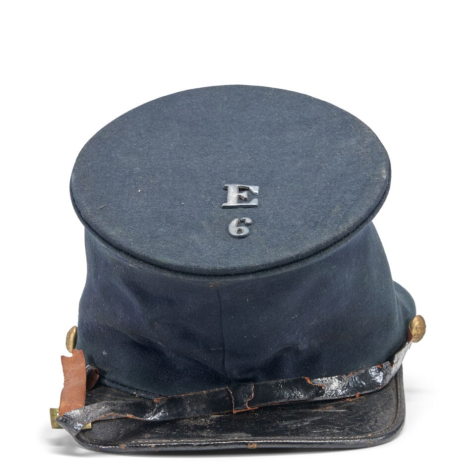 AN IDENTIFIED CIVIL WAR 6TH REGIMENT, COMPANY E FORAGE CAP.: AN IDENTIFIED CIVIL WAR 6TH REGIMENT, COMPANY E FORAGE CAP. Blue cloth body, the top with applied 'E' and '6', eagle 'I' buttons on the sides, remnants of black leather chin strap, tarred visor, the