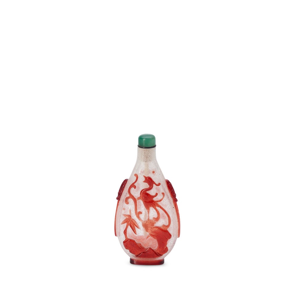 A Red Overlay Glass Oval Snuff Bottle with Phoenix and Bats China,: A Red Overlay Glass Oval Snuff Bottle with Phoenix and Bats China, An oblong bottle with mask ring handles. 3 1/2in (8.9cm) high Lot to be sold without reserve. This lot is subject to the following