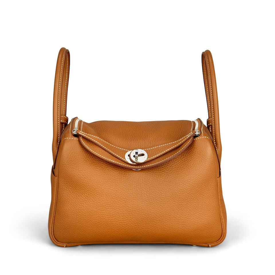 Hermès: a Gold Clemence Leather Lindy 26 2020 (includes rain jacket and dust bag): Hermès: a Gold Clemence Leather Lindy 26 2020 Palladium hardware Condition Grade A 26cm wide, 20cm high, 13cm deep, 9cm handle drop, 30cm shoulder drop, includes rain jacket and dust bag For