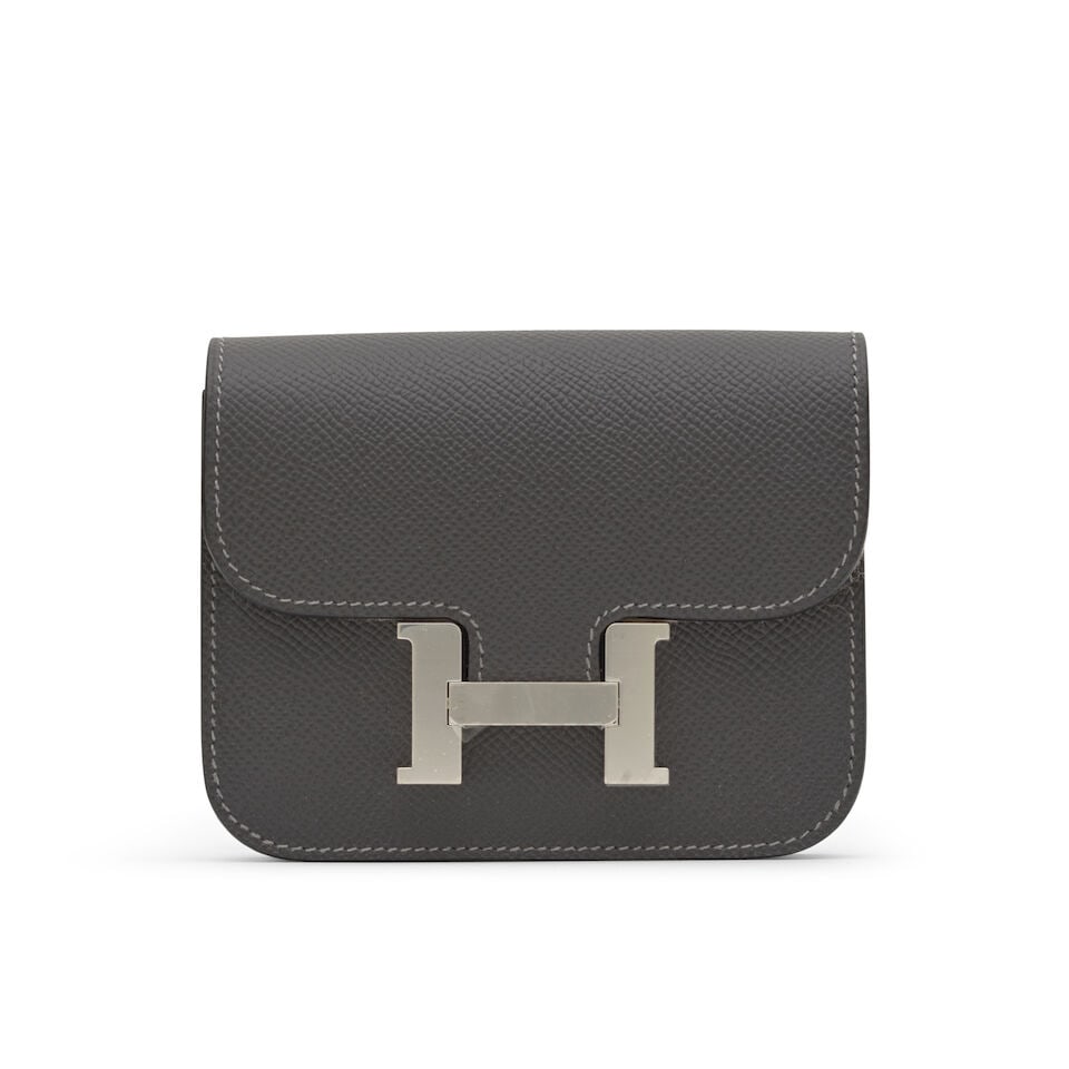 Hermès: a Graphite Epsom Leather Constance Slim Wallet 2024 (includes felt protector, dust ...: Hermès: a Graphite Epsom Leather Constance Slim Wallet 2024 Wallet with belt buckle loop, together with a removable zipped pochette, palladium hardware Condition Grade A 12.5cm wide, 10cm high,