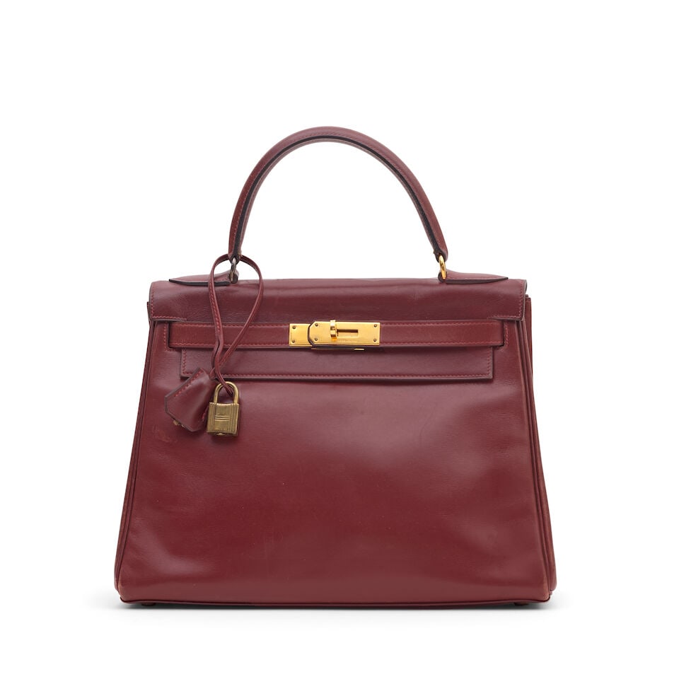 Hermès: a Rouge H Box Leather Retourne Kelly 28 1979 (includes padlock, keys and cloche): Hermès: a Rouge H Box Leather Retourne Kelly 28 1979 Gold tone hardware Condition Grade B- 28cm wide, 21cm high, 11cm deep, 9cm handle drop, includes padlock, keys and cloche For further
