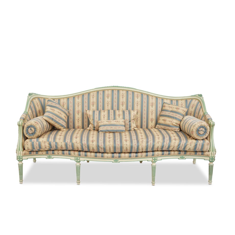 A George III serpentine painted and carved settee: A George III serpentine painted and carved settee The padded serpentine backrest to padded sides and armrests within scroll-carved borders, above a serpentine seat with squab cushion, and six