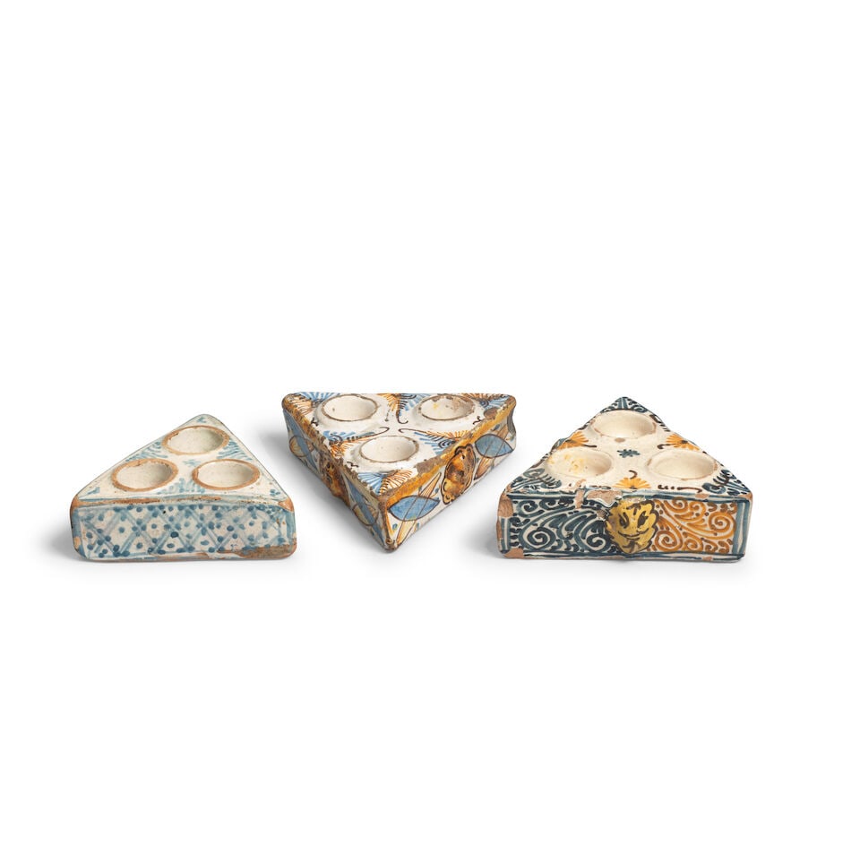 A set of three triangular Spanish spice pots, 17th/18th century: A set of three triangular Spanish spice pots, 17th/18th century Two moulded with masks and decorated in blue and ochre, the third of plainer design decorated with blue trellis patterns, the largest: