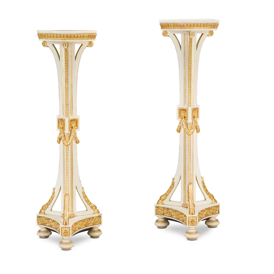 A pair of early 20th century painted and parcel gilt torchèresIn the George III style (2): A pair of early 20th century painted and parcel gilt torchères In the George III style Each with a circular dished top and a stiff-leaf border, on a fluted central support encompassed by three