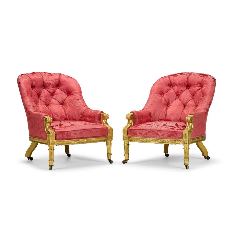 A pair of mid Victorian giltwood low bergères Circa 1875: A pair of mid Victorian giltwood low bergères Circa 1875 Each of tub back form, with stiff-leaf wrapped, volute scroll carved, acanthus clasped and fluted arm terminals, with a bowed entrelac