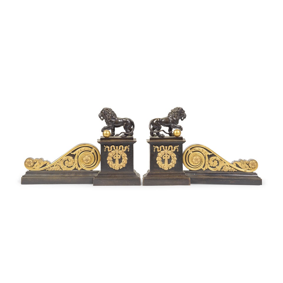 A pair of Charles X patinated and gilt bronze chenets (2): A pair of Charles X patinated and gilt bronze chenets Each formed as a square plinth mounted with a ribbon tied oak wreath and club mounts surmounted by Medici style lions, their front paws resting