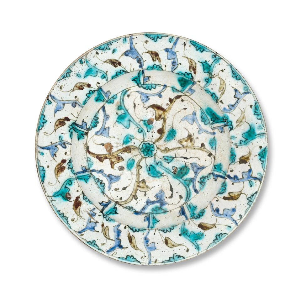An unusual Safavid underglaze-painted pottery bowl Persia, possibly Kubachi, 17th Century: An unusual Safavid underglaze-painted pottery bowl Persia, possibly Kubachi, 17th Century of shallow rounded form on a short foot with a large flattened rim, decorated underglaze in green, blue and re