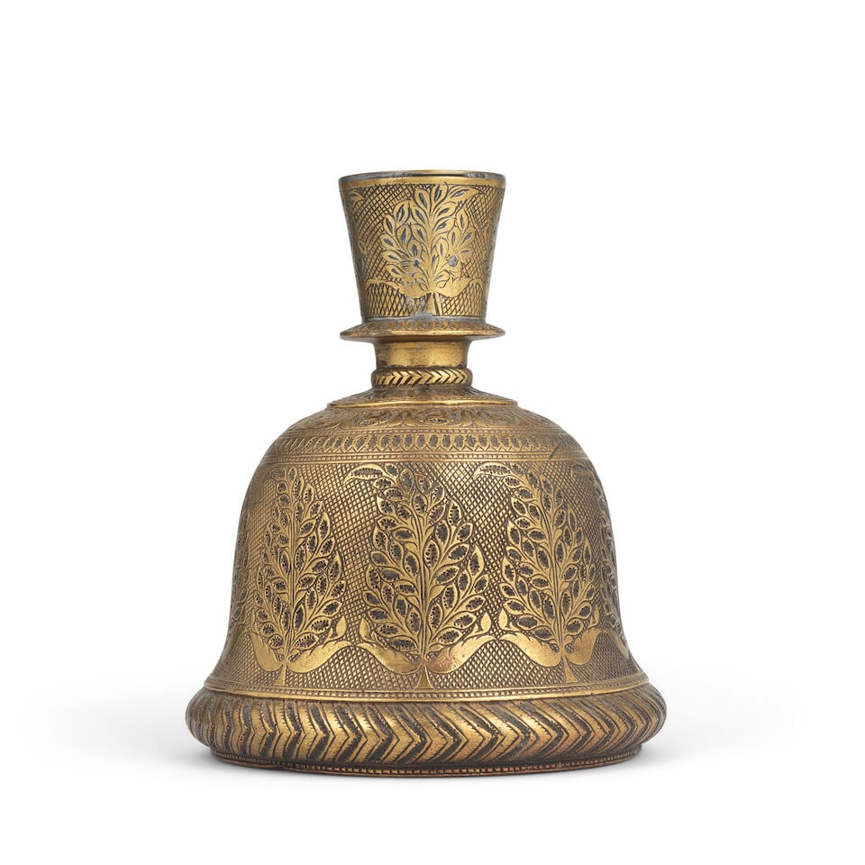 A Mughal brass hookah base Lahore, early 18th Century: A Mughal brass hookah base Lahore, early 18th Century of bell-shaped form, the short flaring neck with moulding and neck ring, engraved with frieze of floral sprays to body and neck, band of rosettes