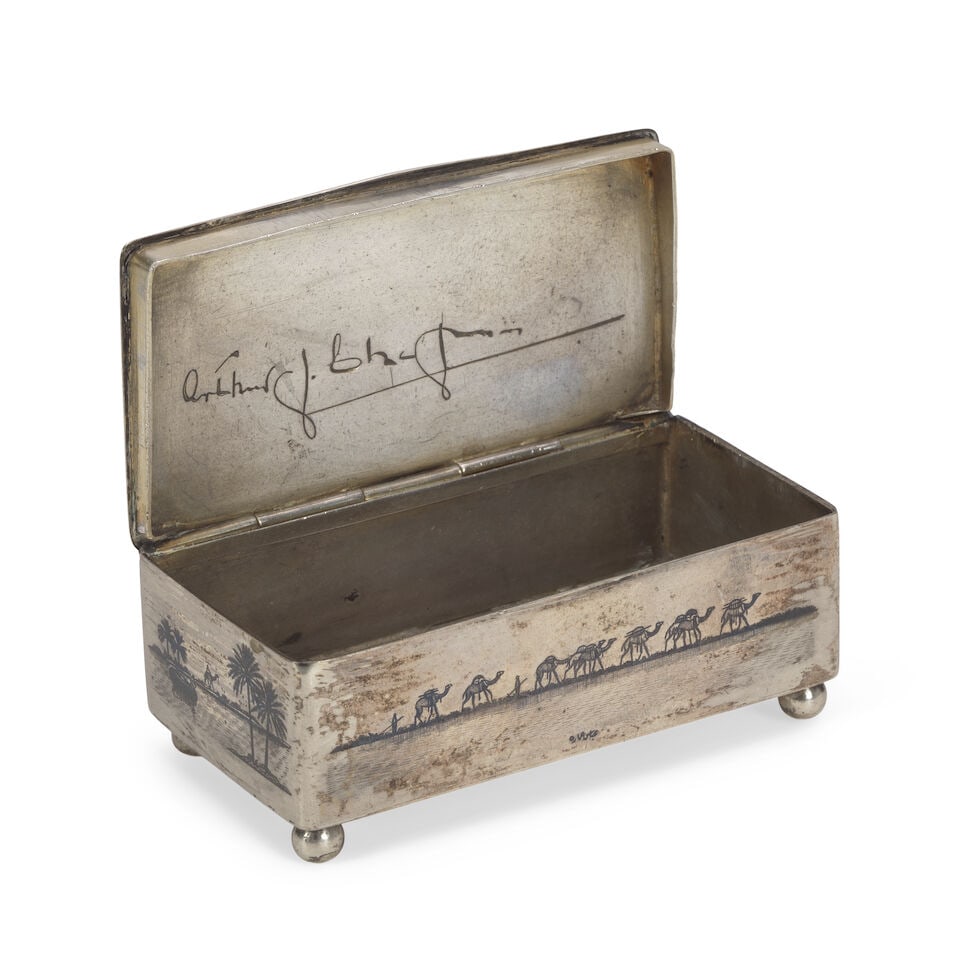 A niello silver snuff box signed by Abbas Umara Iraq, first half of the 20th Century: A niello silver snuff box signed by Abbas Umara Iraq, first half of the 20th Century of rectangular form with hinged lid on four knop feet, engraved and decorated in niello, the top with the Tomb of E