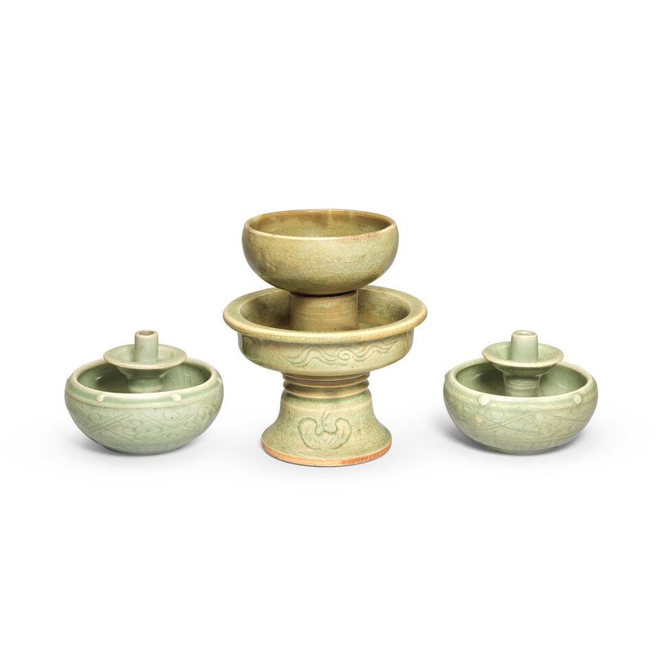 A PAIR OF LONQUAN CELADON TAPER-STICK HOLDERS AND A CELADON-GLAZED CUP AND STAND Ming Dynasty, 1...: A PAIR OF LONQUAN CELADON TAPER-STICK HOLDERS AND A CELADON-GLAZED CUP AND STAND Ming Dynasty, 15th/16th century The pair of taper-stick holders each modelled with a bowl with deeply rounded sides and