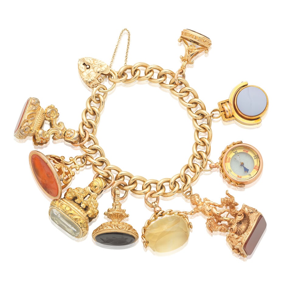 CHARM BRACELET,: CHARM BRACELET, CIRCA 1975 Suspending nine charms including hardstone fobs, a compass and citrine swivel fob UK hallmarks Inner circumference approx. 15.0cm Weight approx. 150.0g Footnotes: OVERALL