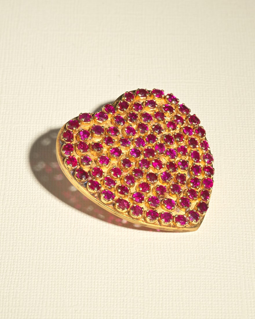 RUBY-SET HEART BROOCH: RUBY-SET HEART BROOCH Oval and circular-cut rubies Length 5.0cm Weight approx. 31.5g Footnotes: OVERALL CONDITION Light surface wear to unhallmarked metal testing as 18kt gold. Some spots of discolou