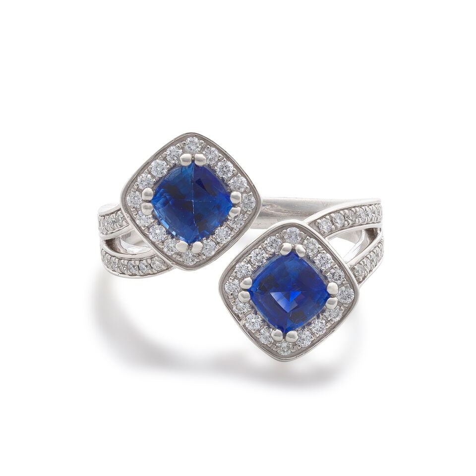 SAPPHIRE AND DIAMOND CROSSOVER RING,: SAPPHIRE AND DIAMOND CROSSOVER RING, 2025 Cushion-shaped sapphires approx. 0.80ct total Brilliant-cut diamonds approx. 0.45ct total Platinum London hallmark, European convention mark Ring size approx.