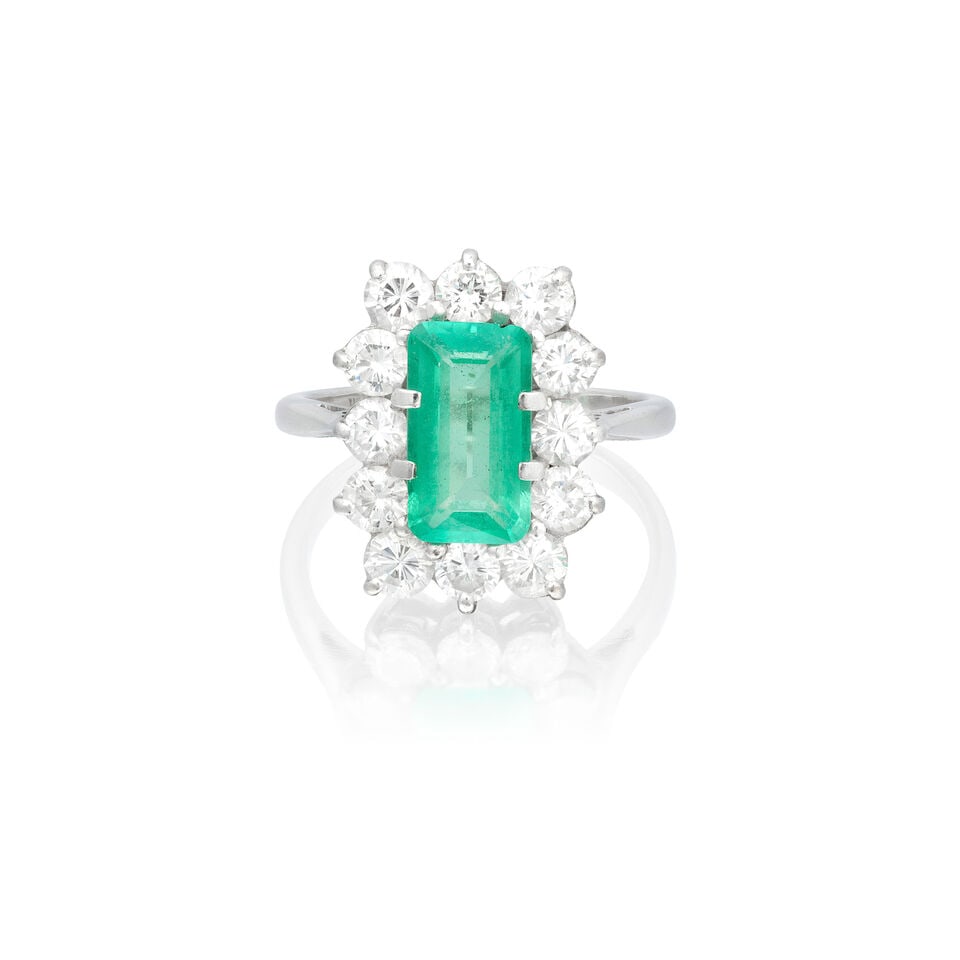 EMERALD AND DIAMOND CLUSTER RING, 1985: EMERALD AND DIAMOND CLUSTER RING, 1985 Step-cut emerald Brilliant-cut diamonds approx. 1.20cts total 18 carat gold London hallmark Ring size approx. L½ Weight approx. 5.0g Footnotes: OVERALL