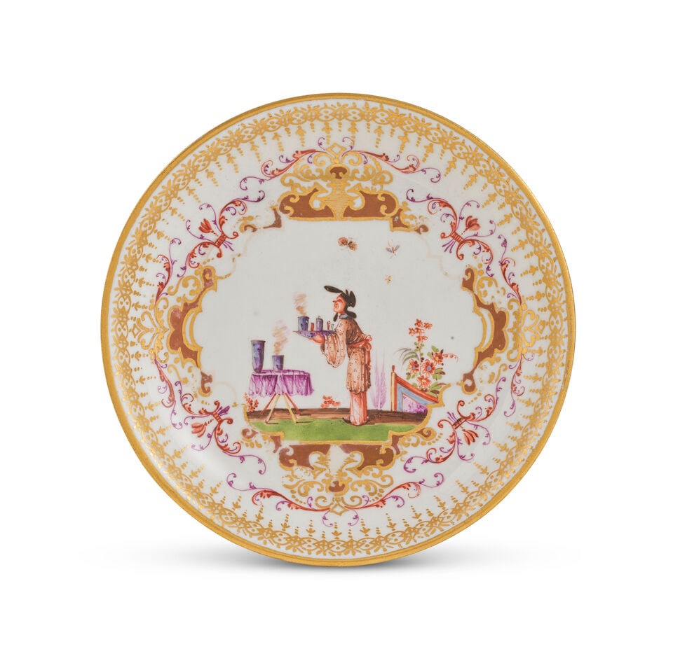 Soucoupe en porcelaine de Meissen, vers 1725-30 A Meissen saucer, circa 1725-30: Soucoupe en porcelaine de Meissen, vers 1725-30 A Meissen saucer, circa 1725-30 Painted with a chinoiserie scene depicting a figure holding a tray in front of a table with two vases, within a gilt