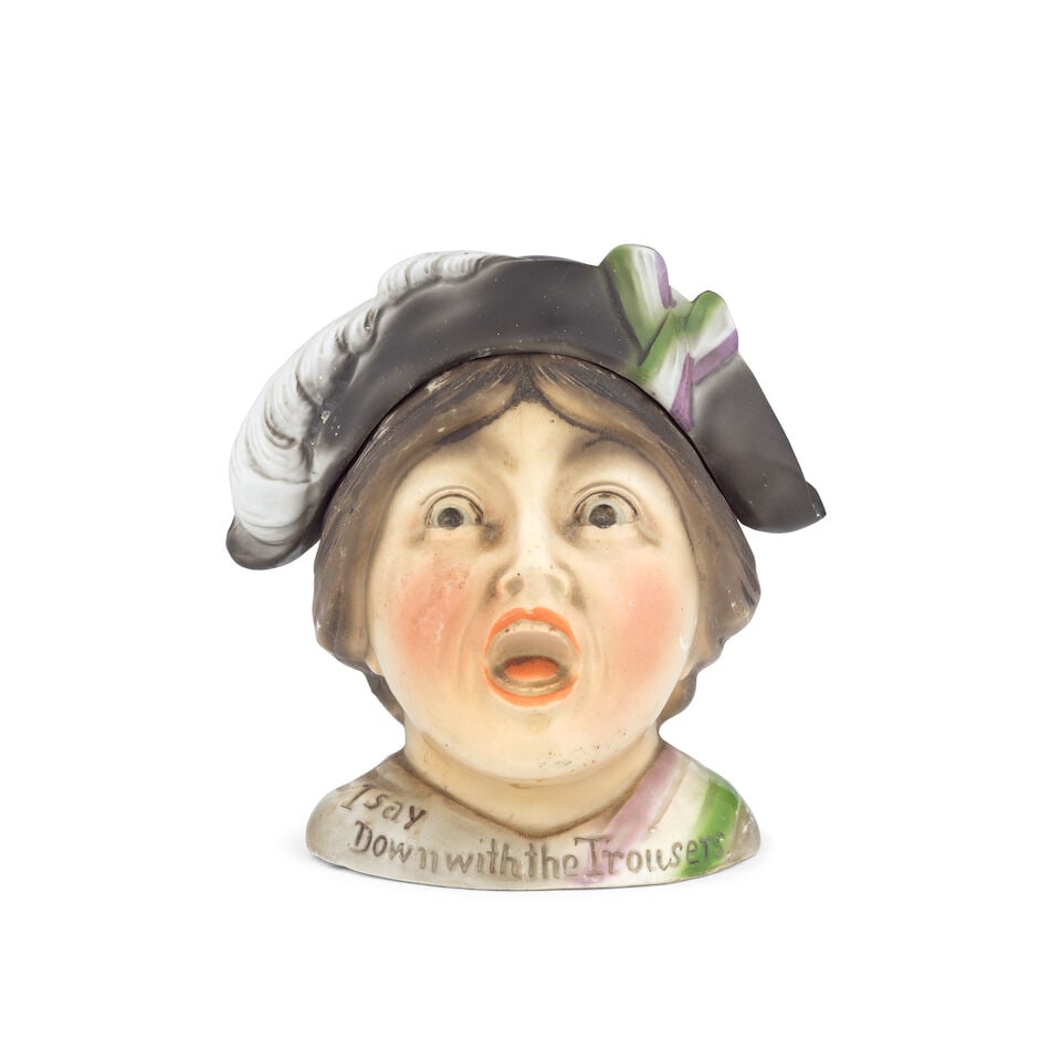 SUFFRAGE CERAMICS Ceramic tobacco or biscuit jar and a crested ware bell (2): SUFFRAGE CERAMICS Ceramic tobacco or biscuit jar in the form of a shouting suffragette, wearing the WSPU colours, bearing the inscription 'I Say Down with the Trousers', her hat forming the removable