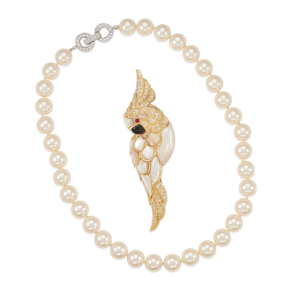 JUDITH LEIBER: COCKATIEL BROOCH AND FAUX PEARL NECKLACE: JUDITH LEIBER: COCKATIEL BROOCH AND FAUX PEARL NECKLACE • One brooch of gold-plated base metal with inlaid mother-of-pearl, carved onyx and Swarovski crystals, signed Judith Leiber, measures 3