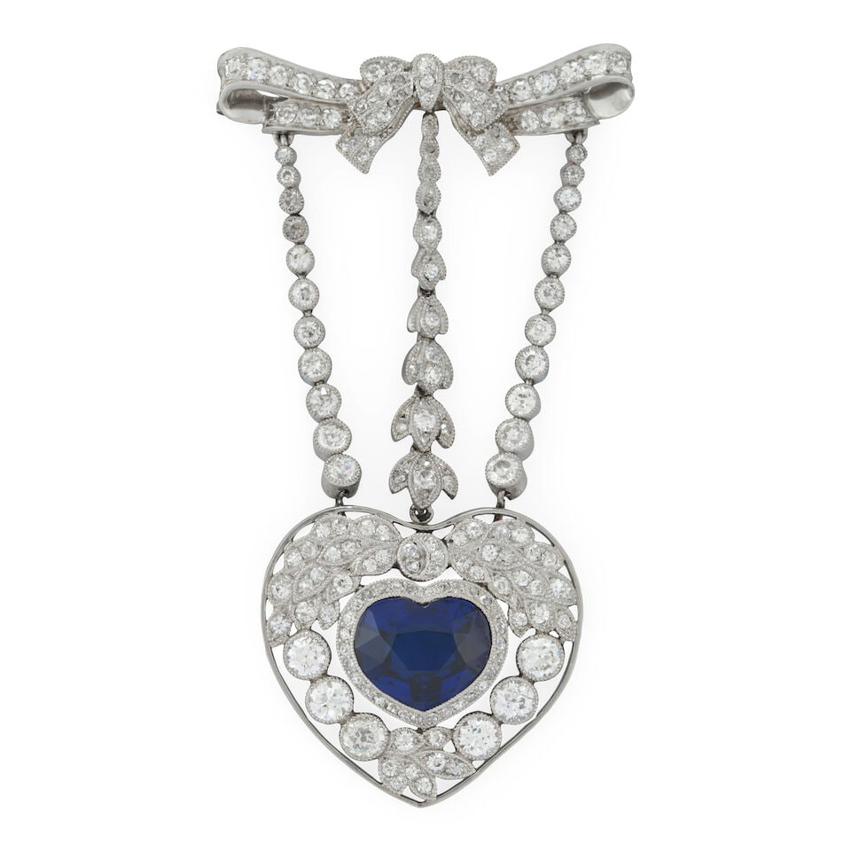 AN EDWARDIAN PLATINUM, SAPPHIRE, AND DIAMOND BROOCH: AN EDWARDIAN PLATINUM, SAPPHIRE, AND DIAMOND BROOCH Designed as a heart centering a bezel-set heart-shape sapphire measuring approximately 8.50 x 10.40 x 4.03 mm, within a garland style border,