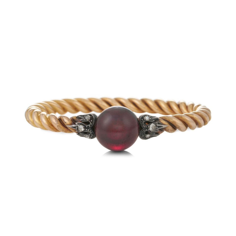 AN ANTIQUE 18K GOLD, GARNET, AND DIAMOND BANGLE BRACELET, FRANCE: AN ANTIQUE 18K GOLD, GARNET, AND DIAMOND BANGLE BRACELET, FRANCE The hinged, ropetwist bangle, centering a bezel-set carbuncle garnet measuring approximately 16.00 mm, with rose-cut diamond accents