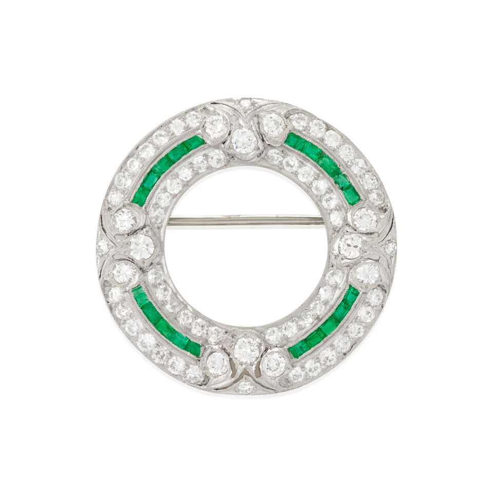 AN ART DECO PLATINUM, EMERALD, AND DIAMOND BROOCH: AN ART DECO PLATINUM, EMERALD, AND DIAMOND BROOCH The circle brooch set with old European-cut diamonds, approximate total weight 1.50 carats, and channel-set emeralds, with pierced platinum and