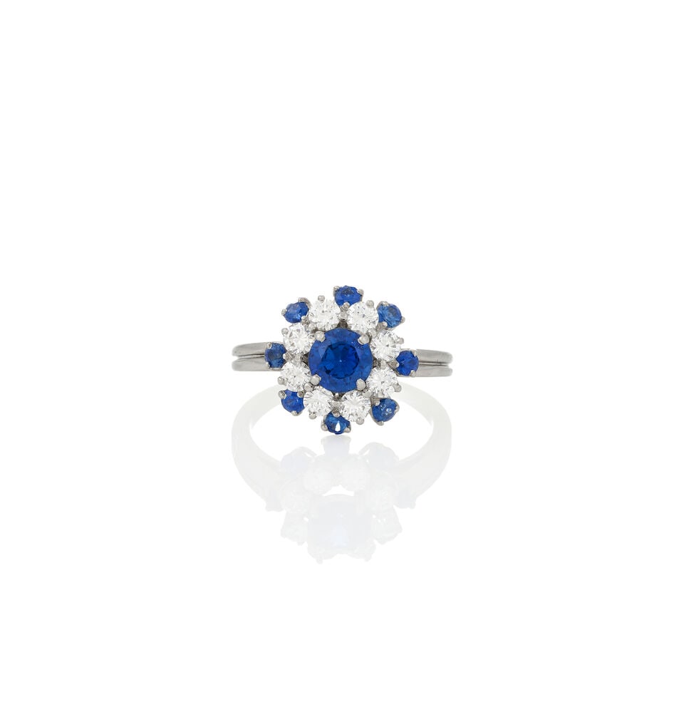 A PLATINUM, SAPPHIRE, AND DIAMOND RING: A PLATINUM, SAPPHIRE, AND DIAMOND RING Centering a circular-cut sapphire measuring approximately 5.60 x 3.25 mm, framed by full-cut diamonds and circular-cut sapphires, weight 4.1 dwt, numbered, 