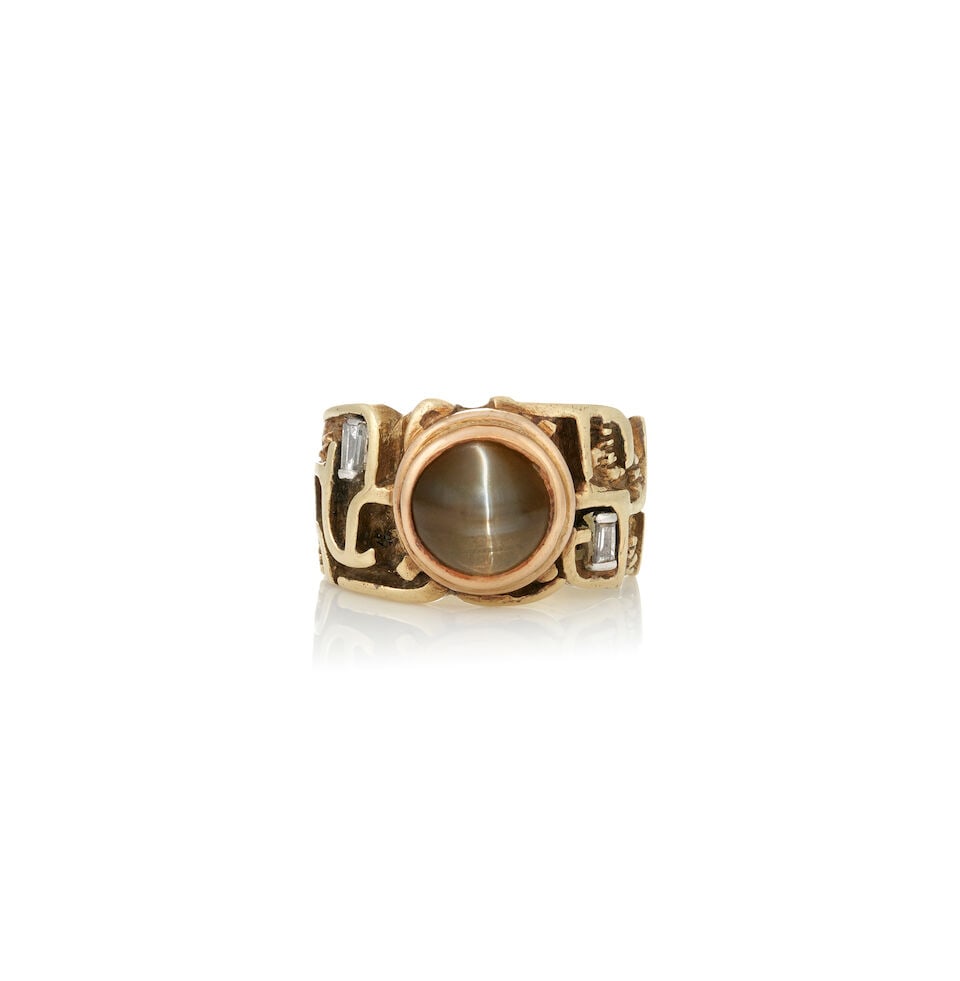 A GOLD, CAT'S EYE CHRYSOBERYL, AND DIAMOND RING: A GOLD, CAT'S EYE CHRYSOBERYL, AND DIAMOND RING Centering a cat's eye chrysoberyl cabochon, bezel-set in a sculptural mount, with tapered baguette-cut diamond accents, weight 6.1 dwt, approximately