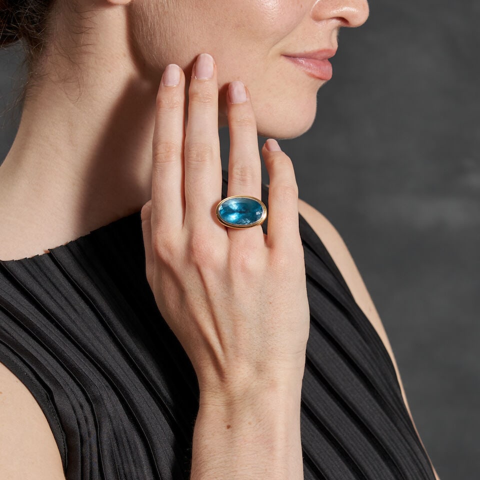 JOHN HARDY: AN 18K GOLD GEM-SET RING: JOHN HARDY: AN 18K GOLD GEM-SET RING Centering a large fancy-cut blue topaz, measuring approximately 23.00 x 15.00 x 9.30 mm, bezel-set in a filigree mount with bezel-set oval and pear shape gemstone