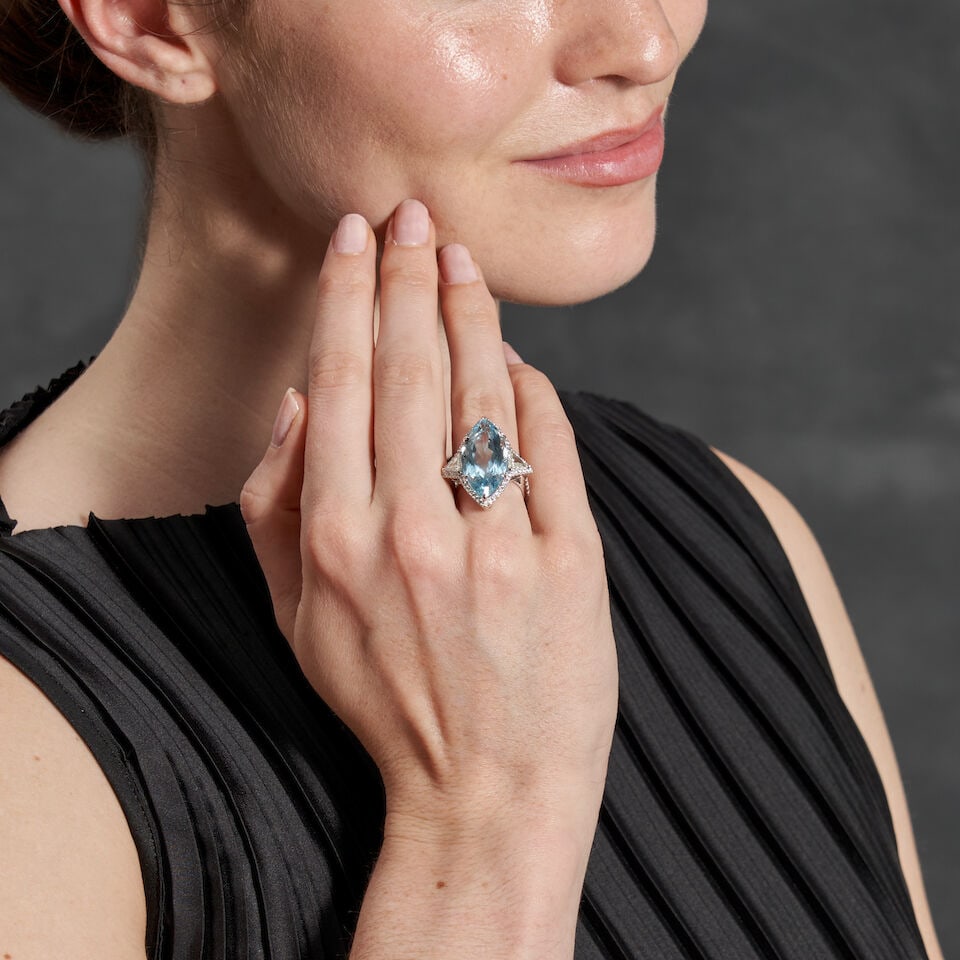 A PLATINUM, AQUAMARINE, AND DIAMOND RING: A PLATINUM, AQUAMARINE, AND DIAMOND RING Centering a fancy-cut aquamarine measuring approximately 24.00 x 12.10 x 8.75 mm, flanked by triangular-cut diamonds, and bordered by full-cut diamonds,