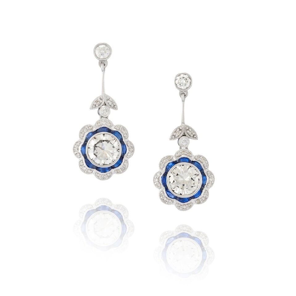 A PAIR OF PLATINUM, SAPPHIRE, AND DIAMOND EARRINGS: A PAIR OF PLATINUM, SAPPHIRE, AND DIAMOND EARRINGS Each centering a bezel-set full-cut diamond, weighing 1.30 and 1.22 carats, framed by calibré-cut sapphires and full-cut diamonds, weight 5.5 dw
