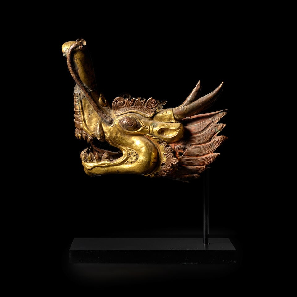 A GILT COPPER ALLOY REPOUSSÉ MAKARA HEAD TIBET, 18TH/19TH CENTURY: A GILT COPPER ALLOY REPOUSSÉ MAKARA HEAD TIBET, 18TH/19TH CENTURY Himalayan Art Resources item no. 8809 10 1/2 in. (26.7 cm) high Footnotes: 西藏