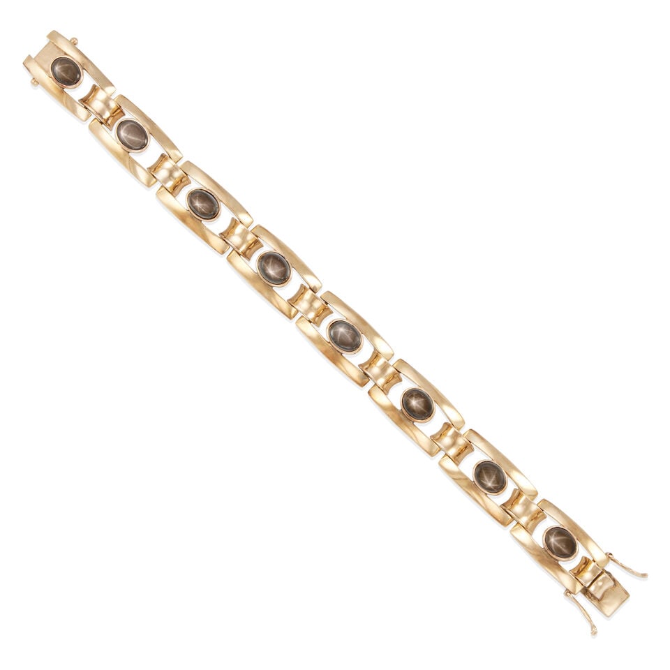 12K GOLD AND STAR SAPPHIRE BRACELET: 12K GOLD AND STAR SAPPHIRE BRACELET • 12k yellow gold • 8 oval black star sapphire cabochons weighing approximately 17.00 - 20.00 carats total • Length 6 3/4 in. • Estimated