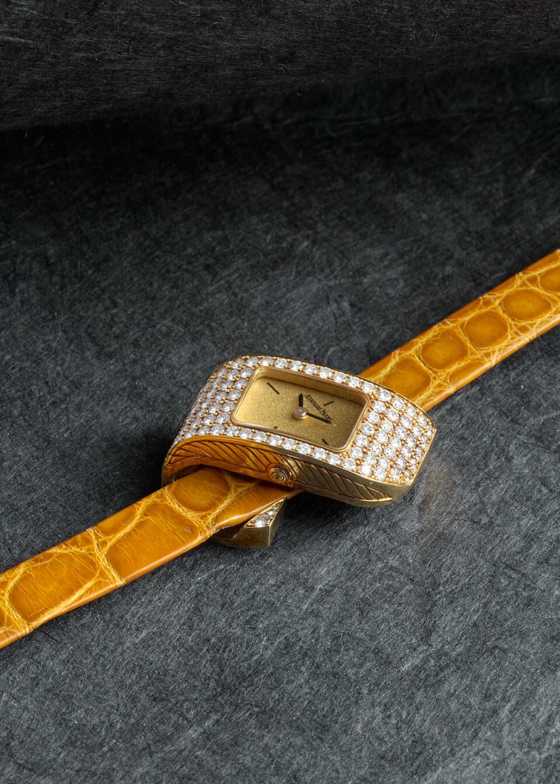 AUDEMARS PIGUET. AN 18K GOLD AND DIAMOND SET QUARTZ WRISTWATCHc. 1990s: AUDEMARS PIGUET. AN 18K GOLD AND DIAMOND SET QUARTZ WRISTWATCH Date: c. 1990s Movement: Cal. 2601, 3-jewel quartz, no. 454100 Dial: Champagne Case: Ribbon-form rectangular, case back secured by 4 scre