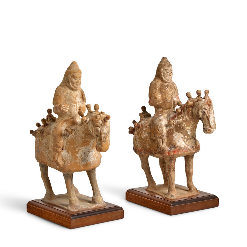 A PAIR OF PAINTED AND GILT-DECORATED POTTERY HORSES AND RIDERS IN MILITARY ATTIRE Northern Dynas...: A PAIR OF PAINTED AND GILT-DECORATED POTTERY HORSES AND RIDERS IN MILITARY ATTIRE Northern Dynasties 11 1/2in (29.2cm) high (wood stands). Footnotes: 北朝 加彩描金