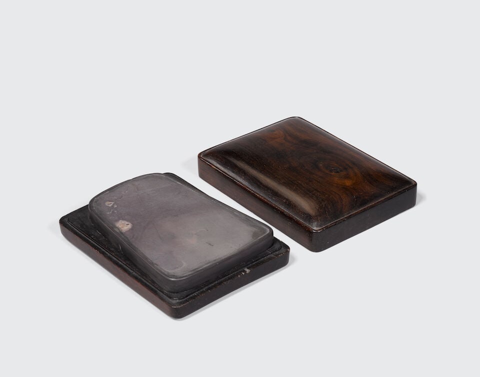 A DUAN INKSTONE AND HARDWOOD BOX Qing Dynasty: A DUAN INKSTONE AND HARDWOOD BOX Qing Dynasty 5 1/4in (13.4cm) length of stone; 6in (15.2cm) length of box Footnotes: 清 端硯暨硬木蓋盒 Provenance MD