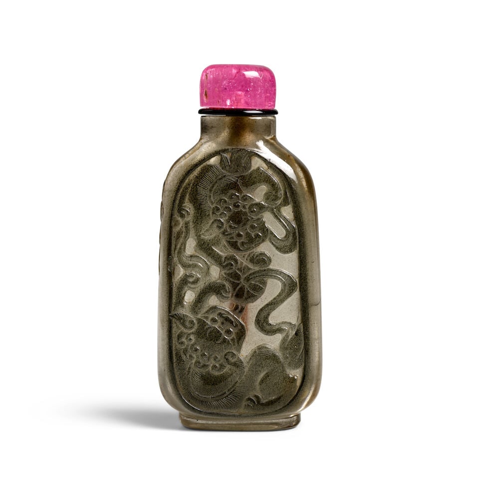 A GRAY-GREEN-SKINNED SMOKY CRYSTAL 'TWO BUDDHISTIC LIONS, RIBBONED BALL AND BAT' SNUFF BOTTLE 1...: A GRAY-GREEN-SKINNED SMOKY CRYSTAL 'TWO BUDDHISTIC LIONS, RIBBONED BALL AND BAT' SNUFF BOTTLE 1800-1900 2 3/4in (7cm) high, stopper Footnotes: 1800-1900