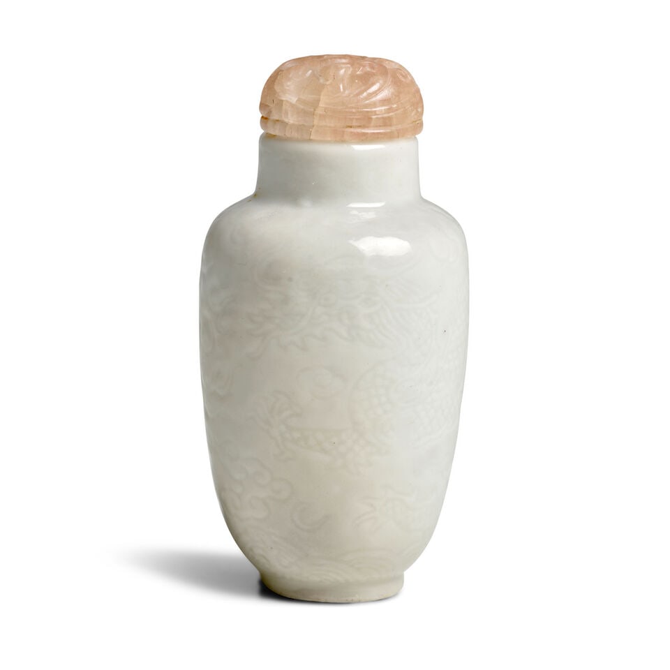 A WHITE GLAZED INCISED 'DRAGONS ABOVE WAVES' PORCELAIN SNUFF BOTTLE 1800-1900, Qianlong incised...: A WHITE GLAZED INCISED 'DRAGONS ABOVE WAVES' PORCELAIN SNUFF BOTTLE 1800-1900, Qianlong incised four-character seal mark to the base 2 1/2in (6.3cm) high, stopper Footnotes: 1800-1900 白釉