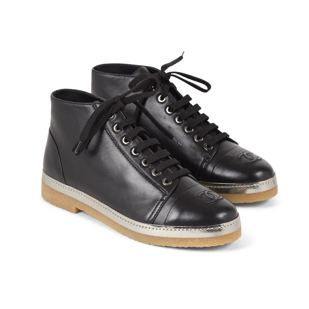 CHANEL. Paire de baskets montantes en cuir noir et argent. Directeur artistique : Karl Lagerfeld.: CHANEL. Paire de baskets montantes en cuir noir et argent. Directeur artistique : Karl Lagerfeld. Empeignes surpiquées du sigle de la Maison, semelles en caoutchouc. Condition d'état: A. Tai