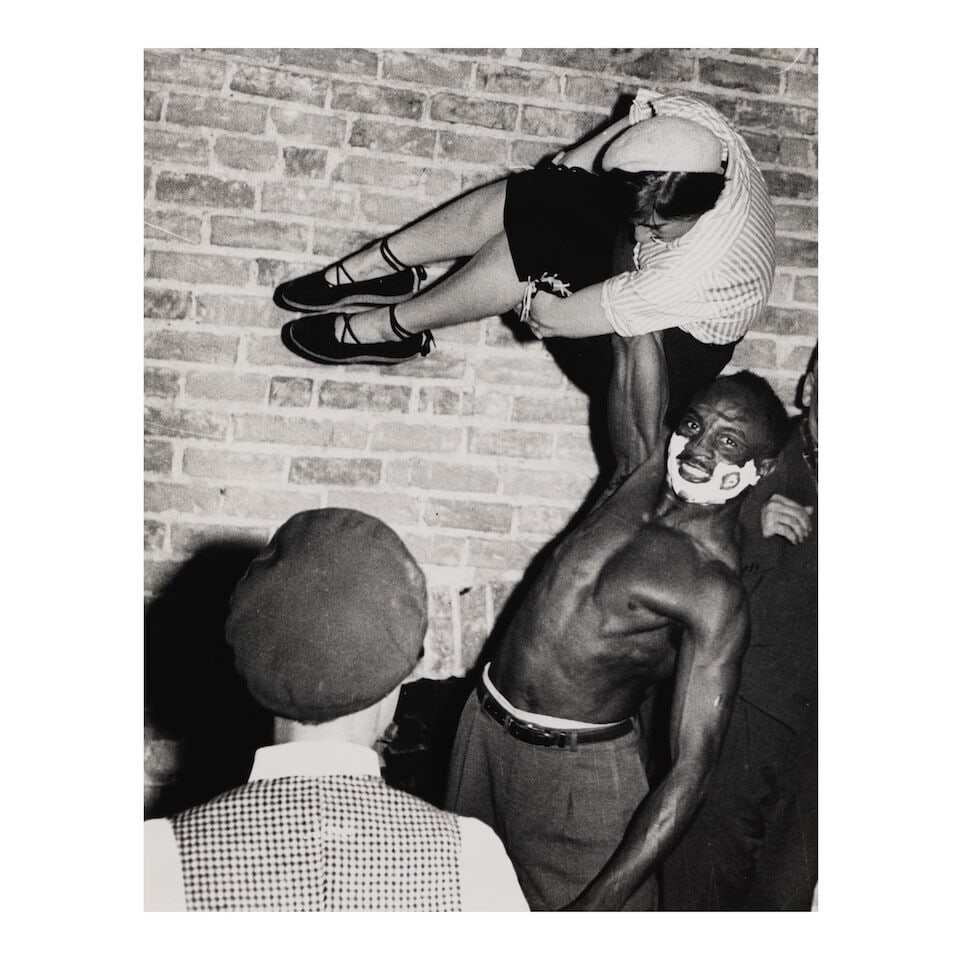 Weegee (Arthur Fellig) (1899-1968); Untitled (Man Lifting Woman with One Hand);: Weegee (Arthur Fellig) (1899-1968) Untitled (Man Lifting Woman with One Hand), c. 1950 Gelatin silver print, printed later; the photographer's circular 'Credit Photo by Weegee the Famous' stamp on the
