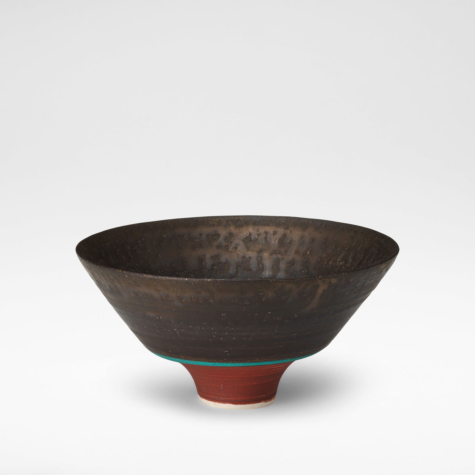 Lucie Rie Footed bowl, circa 1983: Lucie Rie Footed bowl, circa 1983 Porcelain, with manganese, terracotta, turquoise and pale green banding, and a manganese drip to the rim. 8.5 cm high, 16.7 cm diameter Underside impressed with artis